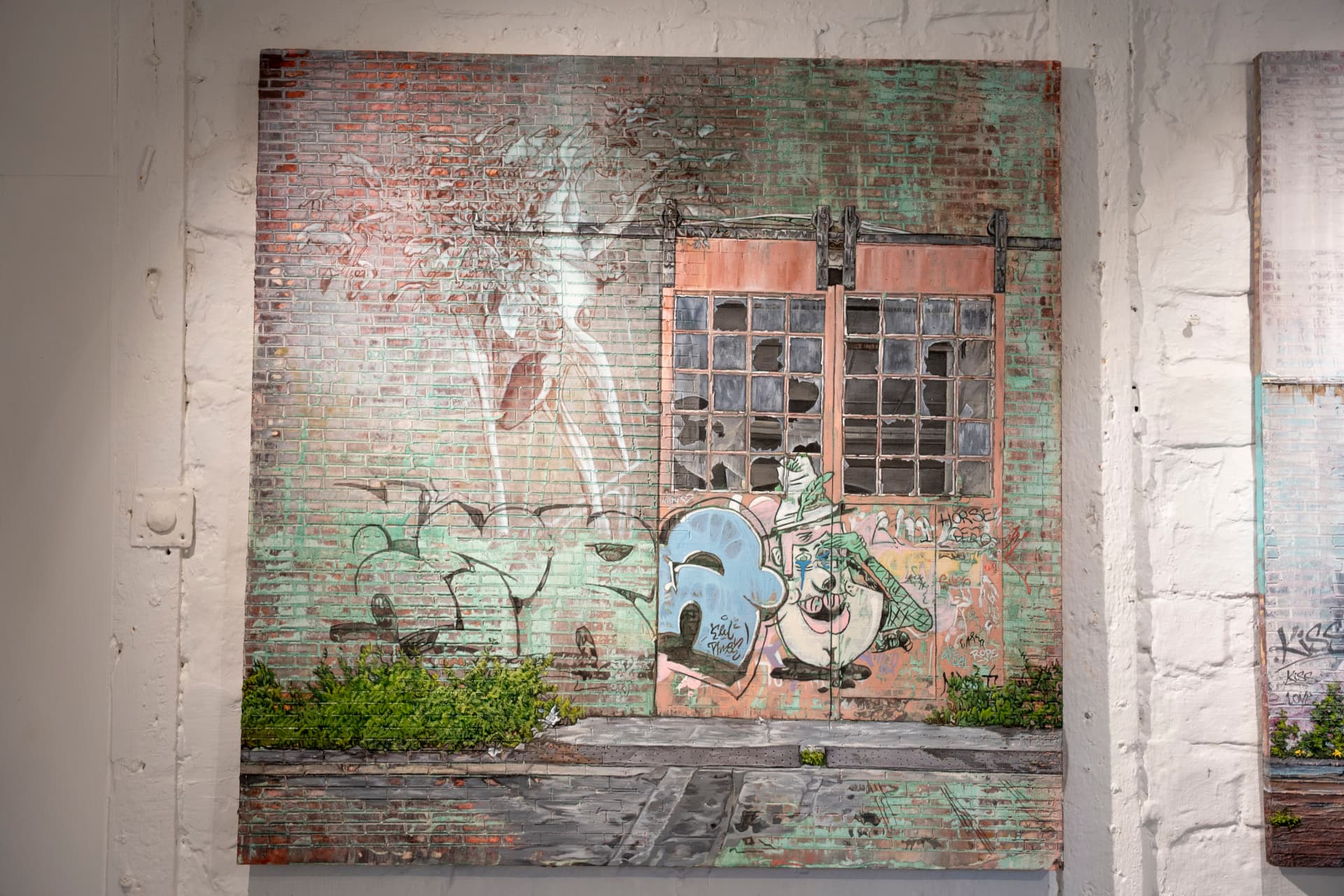 A large painting hanging on a whitewashed studio wall